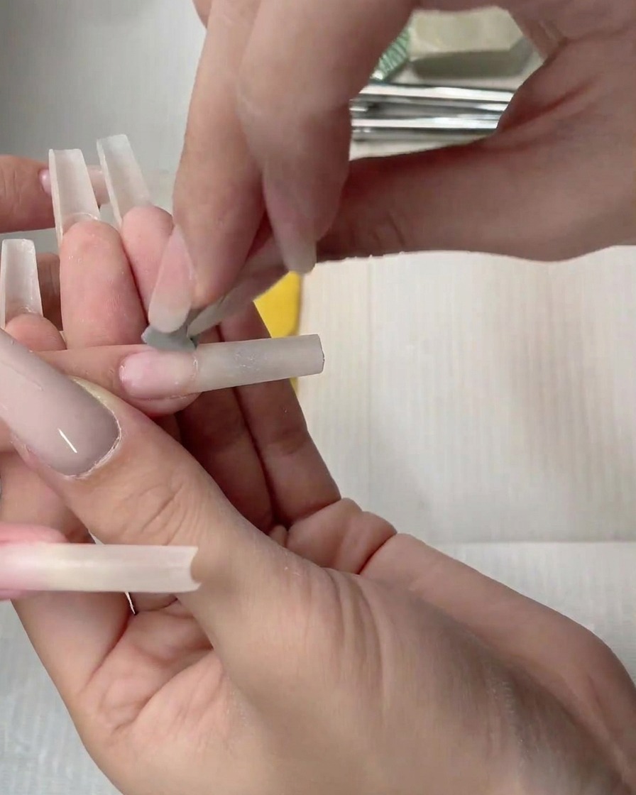 Un aplicador de esponja dando toques de gel nude sobre la uña para difuminar el color.
