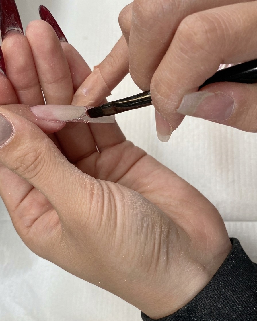 Un pincel plano arrastrando el glitter hacia abajo para crear un efecto ombré.