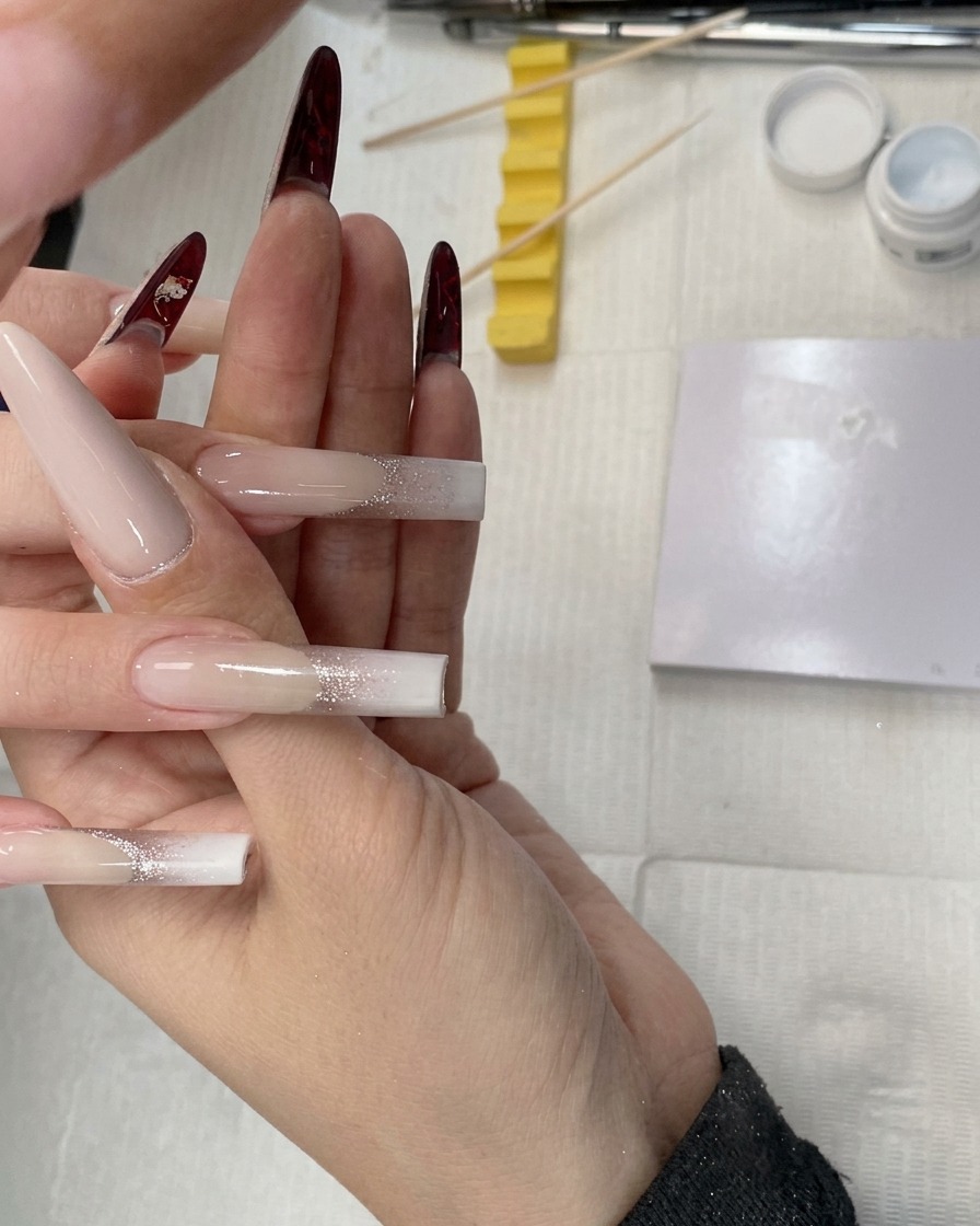 Primer plano de una esponja siendo usada para aplicar gel blanco en la punta de una uña water pipe square.