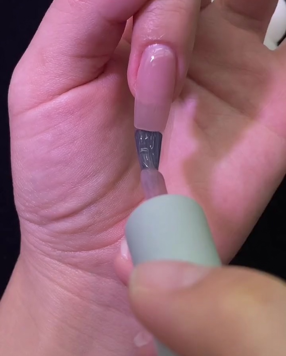 Una mano dentro de una lámpara UV/LED profesional durante el proceso de curado.