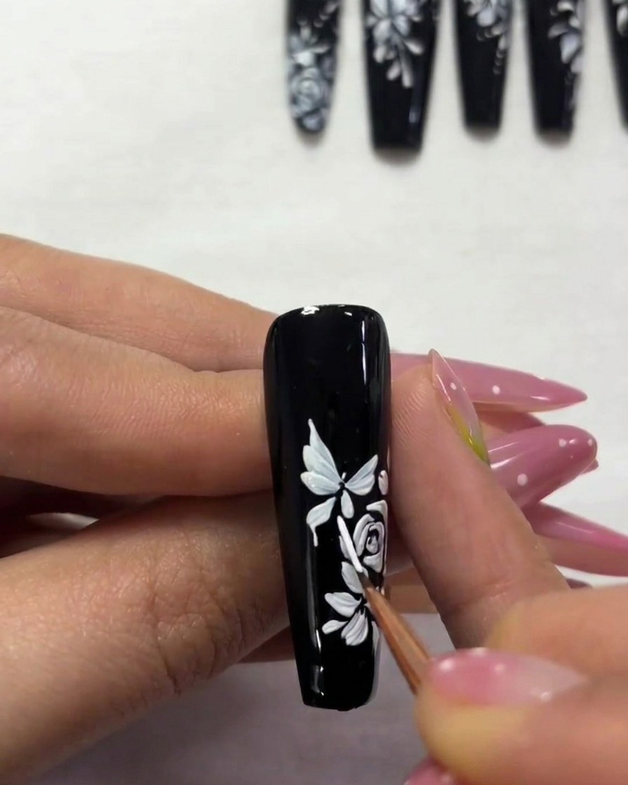 Primer plano de una uña mostrando una segunda mariposa más pequeña siendo pintada hacia el borde superior.
