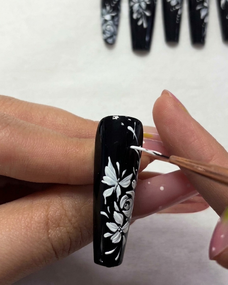Un pincel aplicando un top coat transparente sobre el diseño floral terminado.