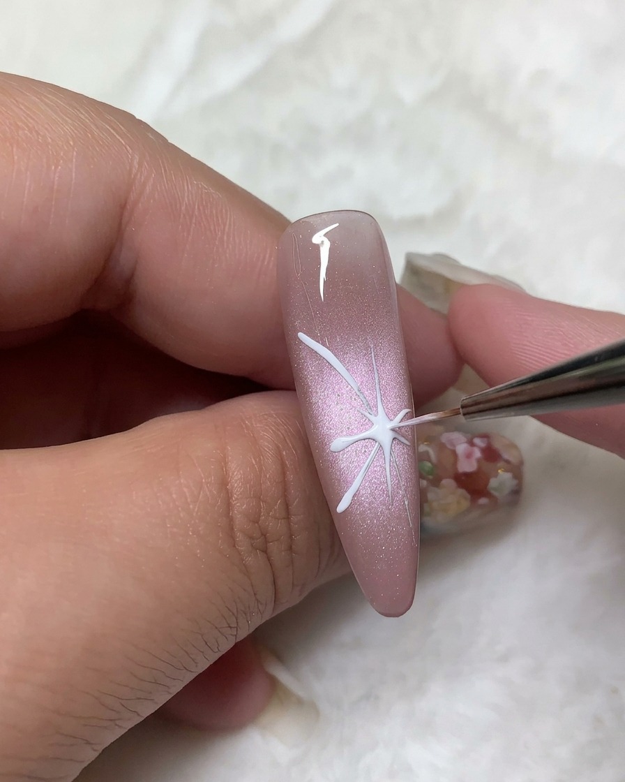 Un pincel de detalle rellenando los contornos de las alas superiores de la mariposa con esmalte en gel blanco opaco.