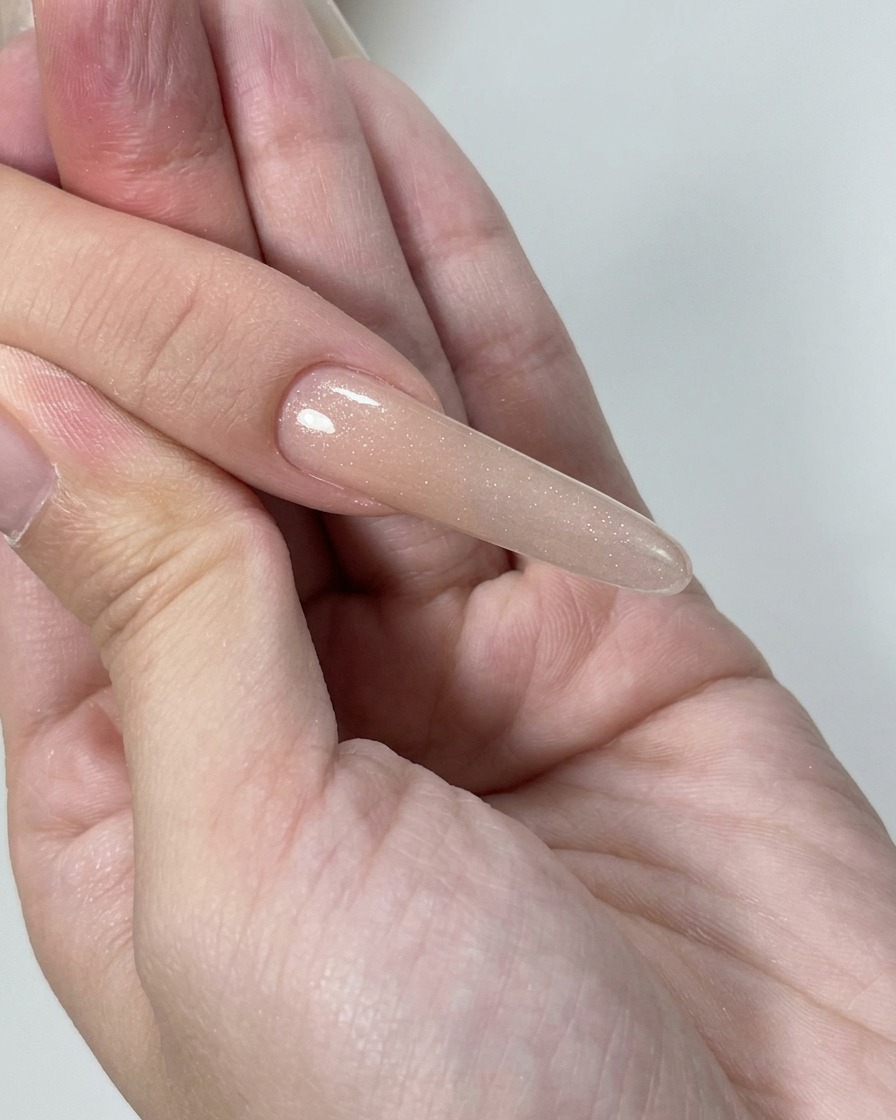 Primer plano de un bloque pulidor refinando la superficie de las uñas de gel para lograr un aspecto suave y uniforme.