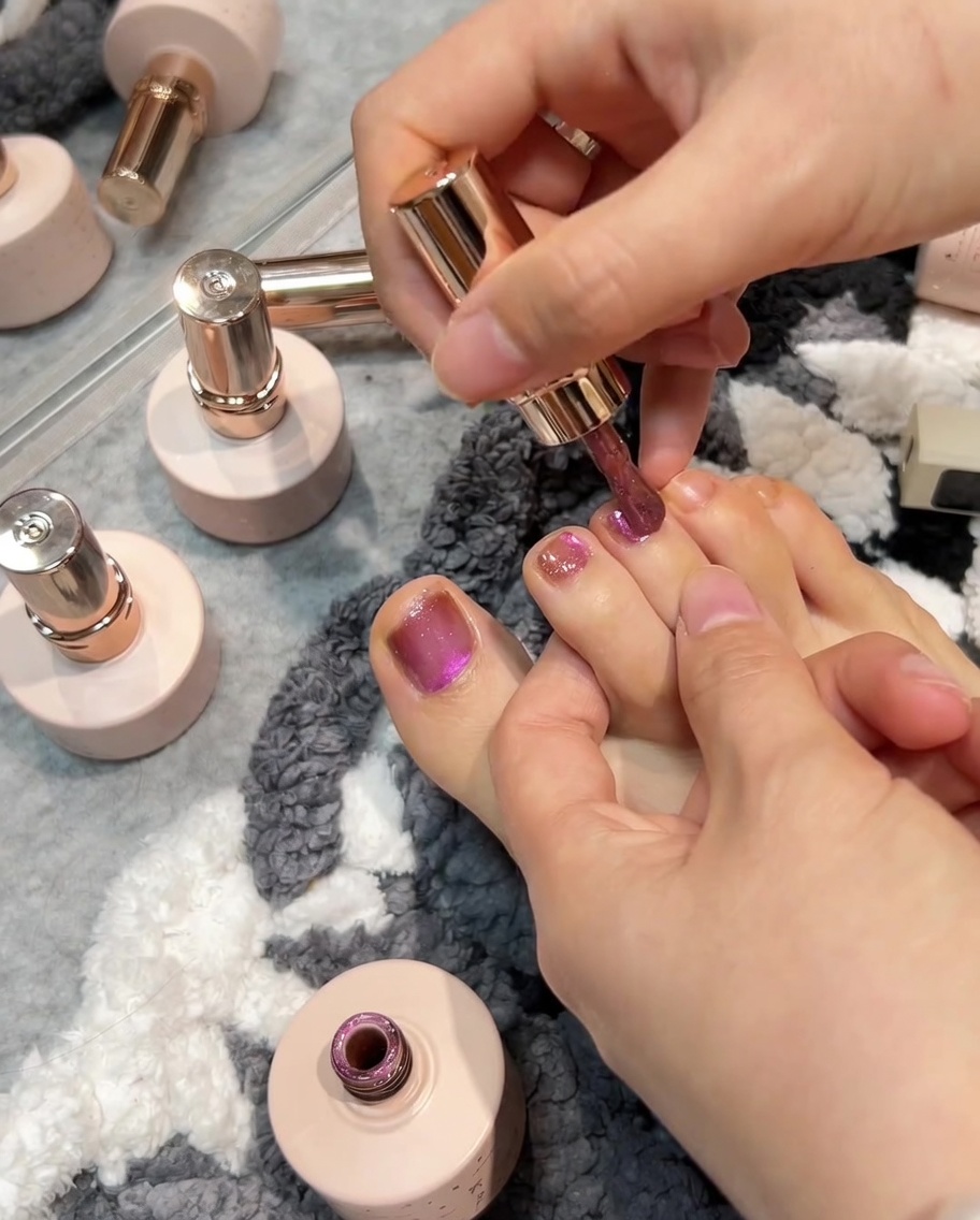 Pincel aplicando esmalte y magnetizándolo sobre la tercera uña.