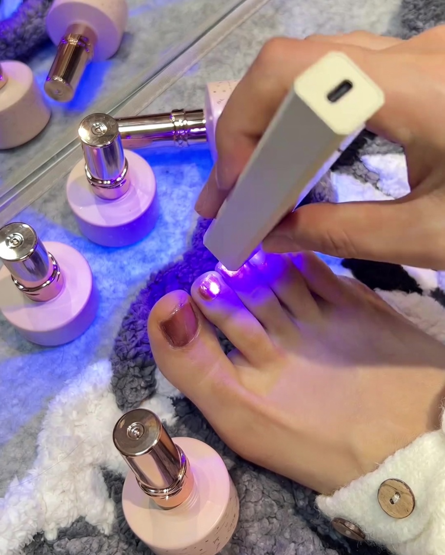 Lámpara UV/LED sobre una uña rosa durante el proceso de curado.