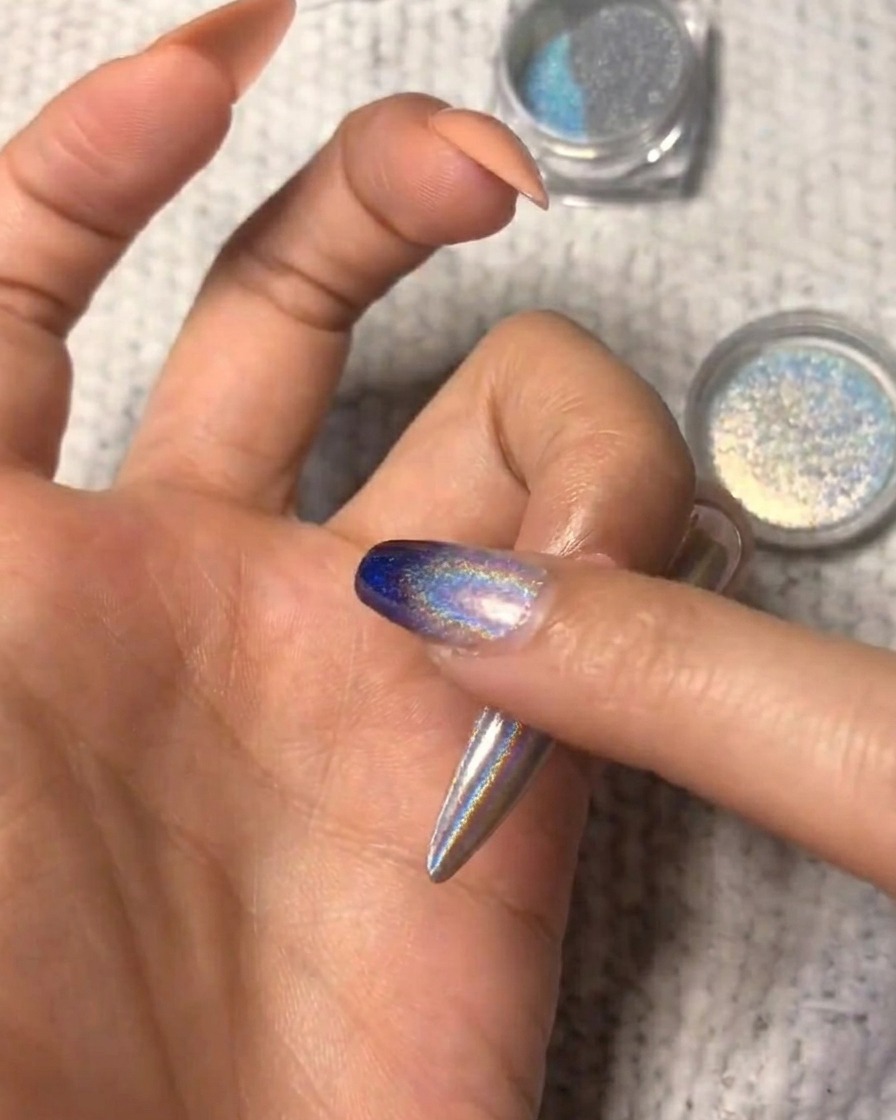 Primer plano mostrando el polvo holográfico siendo difuminado en la uña para un look ombré.