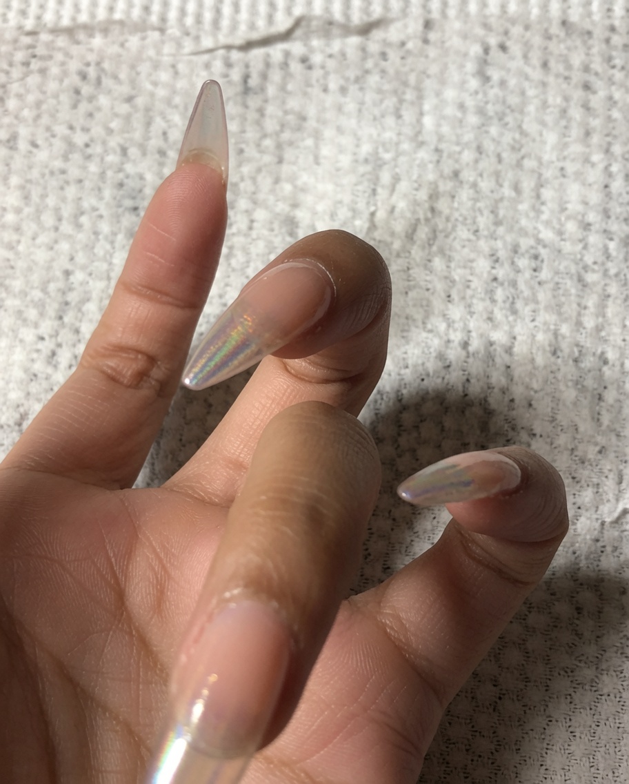 Una mano usando un pequeño pulidor para limar el borde frontal de una uña.