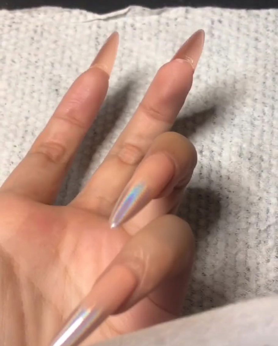 Una mano usando un pequeño pulidor para limar el borde frontal de una uña del dedo índice.