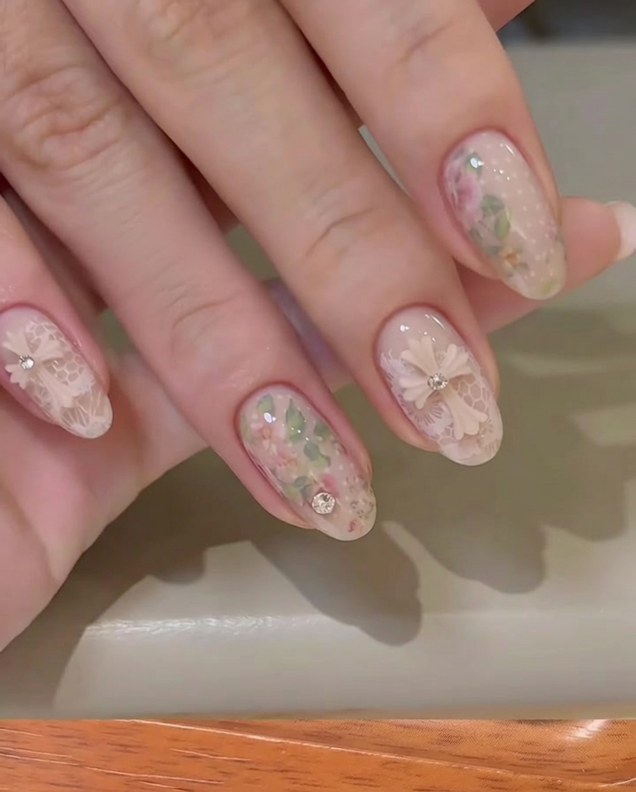 Primer plano de una mano retirando el respaldo de un foil floral de una uña nude.