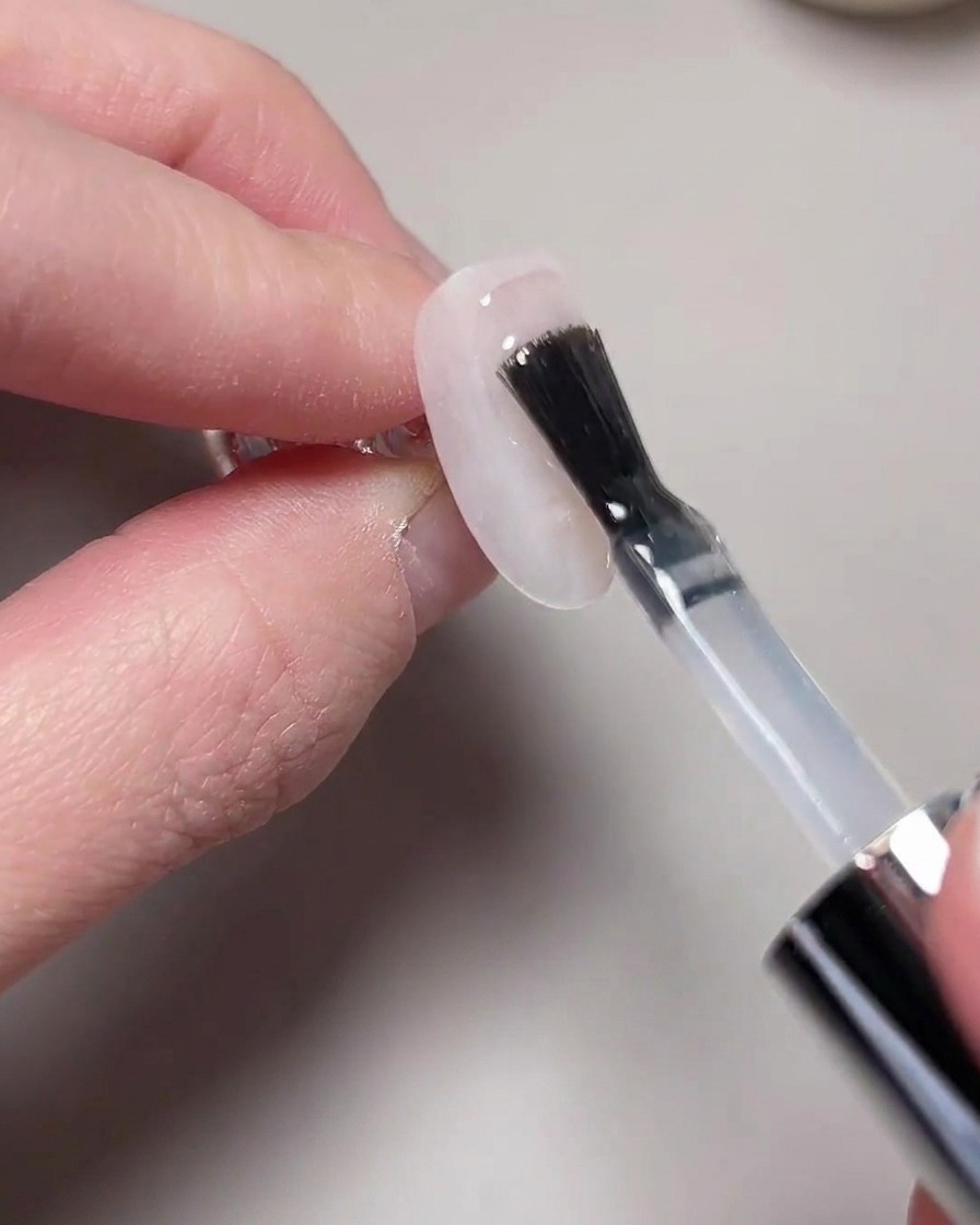 Una mano posicionada dentro de una lámpara UV/LED para el curado.