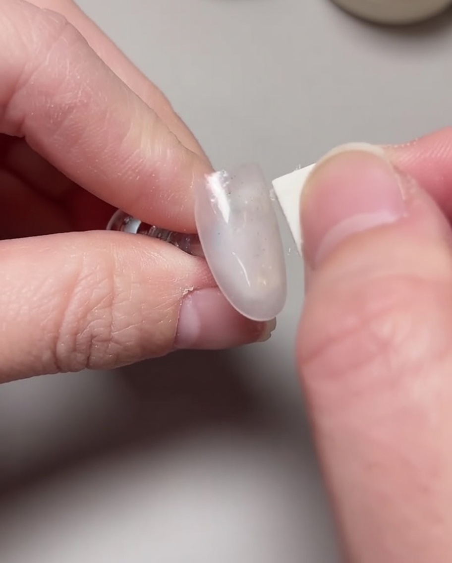 Un pincel aplicando una segunda capa de esmalte de gel rosa lichi para aumentar la opacidad.