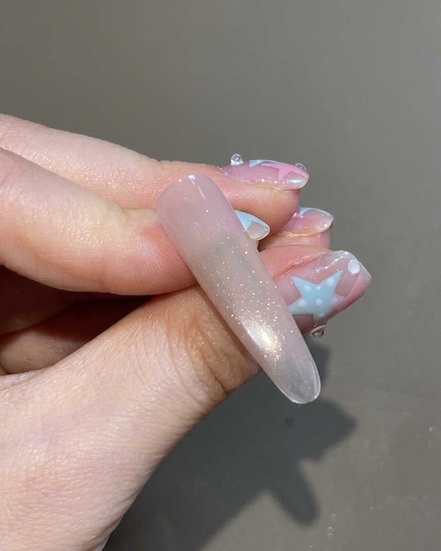 Un pincel aplicando un top coat transparente sobre la uña con efecto ojo de gato totalmente magnetizada.