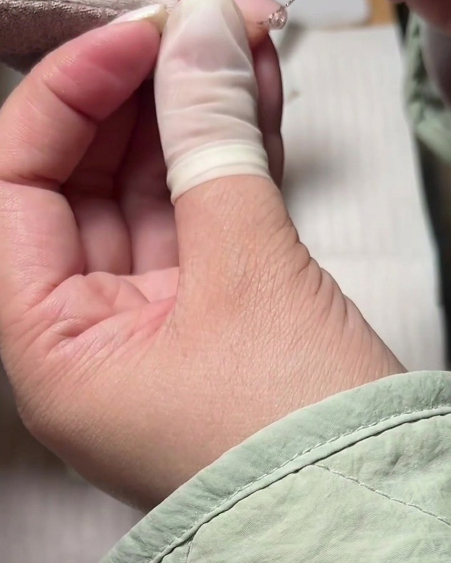 Un pincel liner fino creando una línea de sonrisa francesa con glitter plateado sobre una base nude.