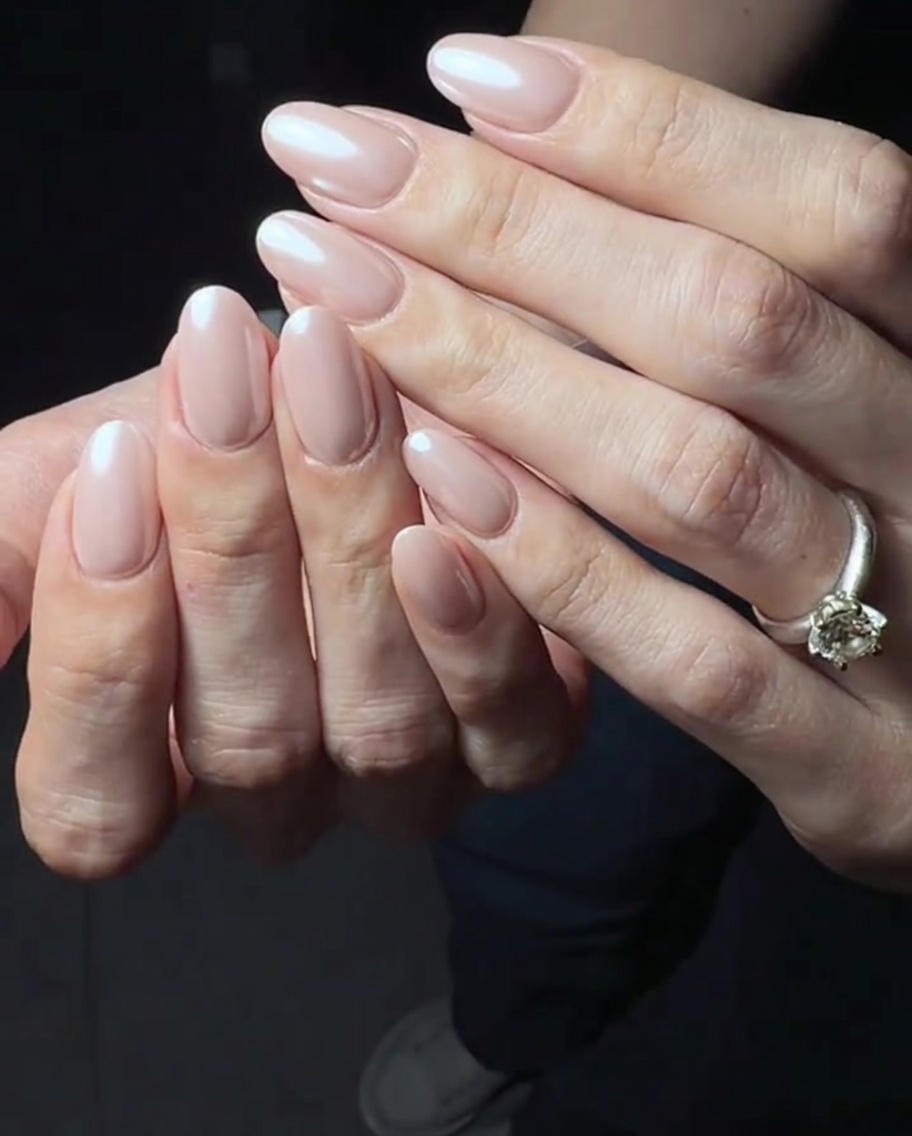 Una capa fina y brillante de top coat siendo aplicada sobre la base de gel rosa.