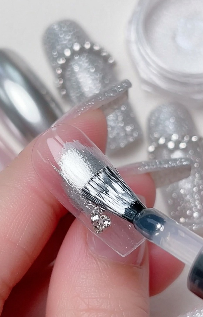 Un pincel de detalle colocando un cristal brillante pequeño en la intersección de los remolinos de gel.