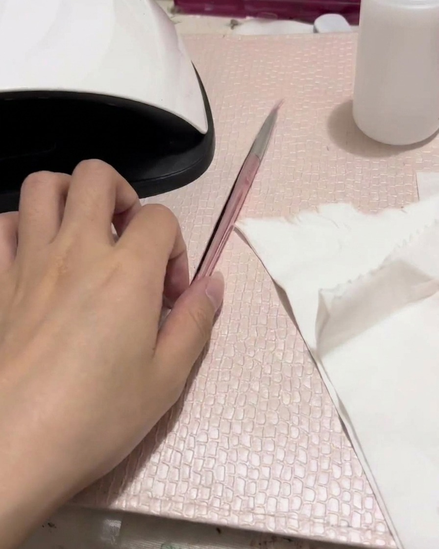 Un aerógrafo siendo probado sobre un pañuelo de papel blanco, mostrando un patrón de spray rosa suave.