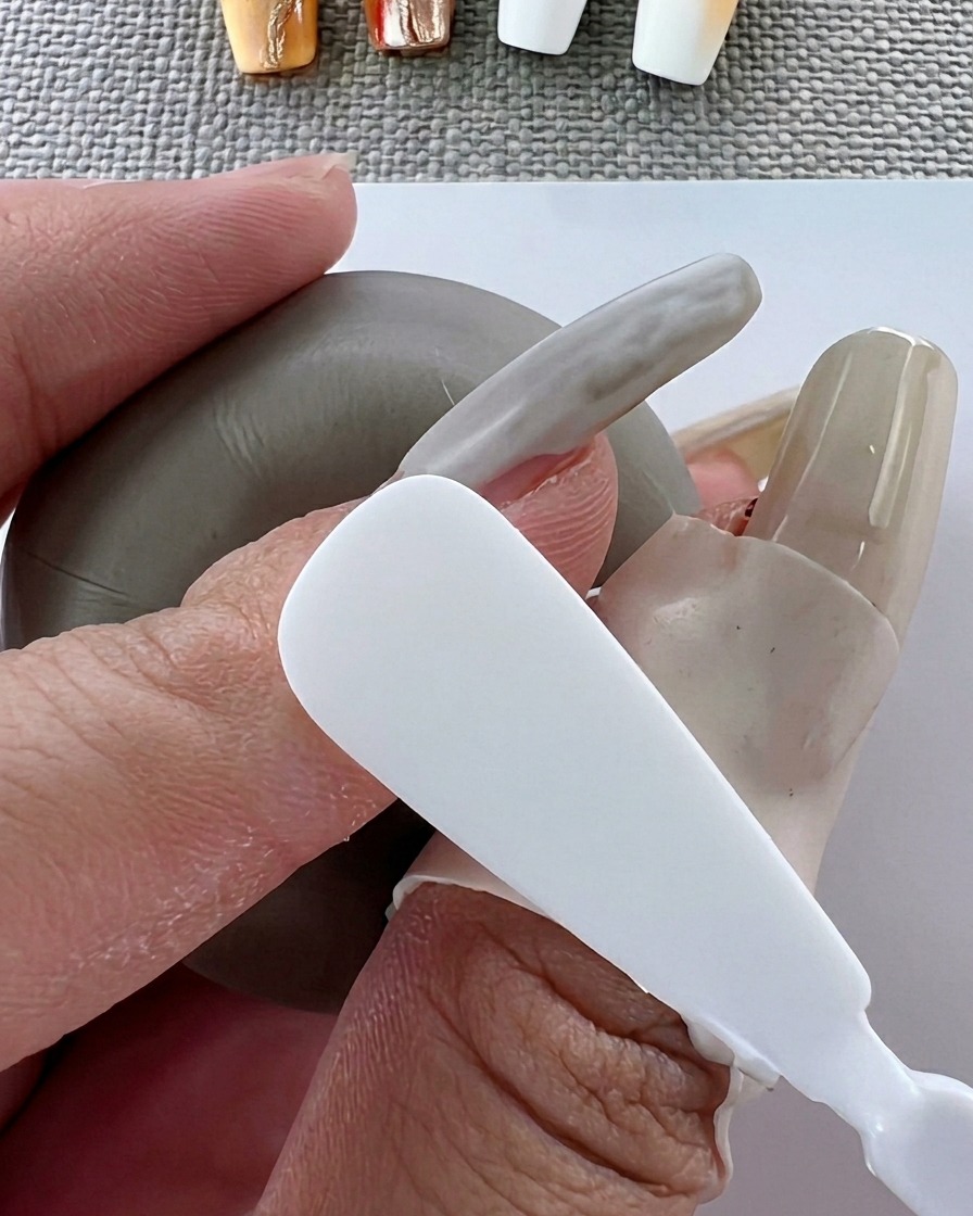 Un pincel aplicando esmalte de gel blanco suave sobre la superficie de la uña.