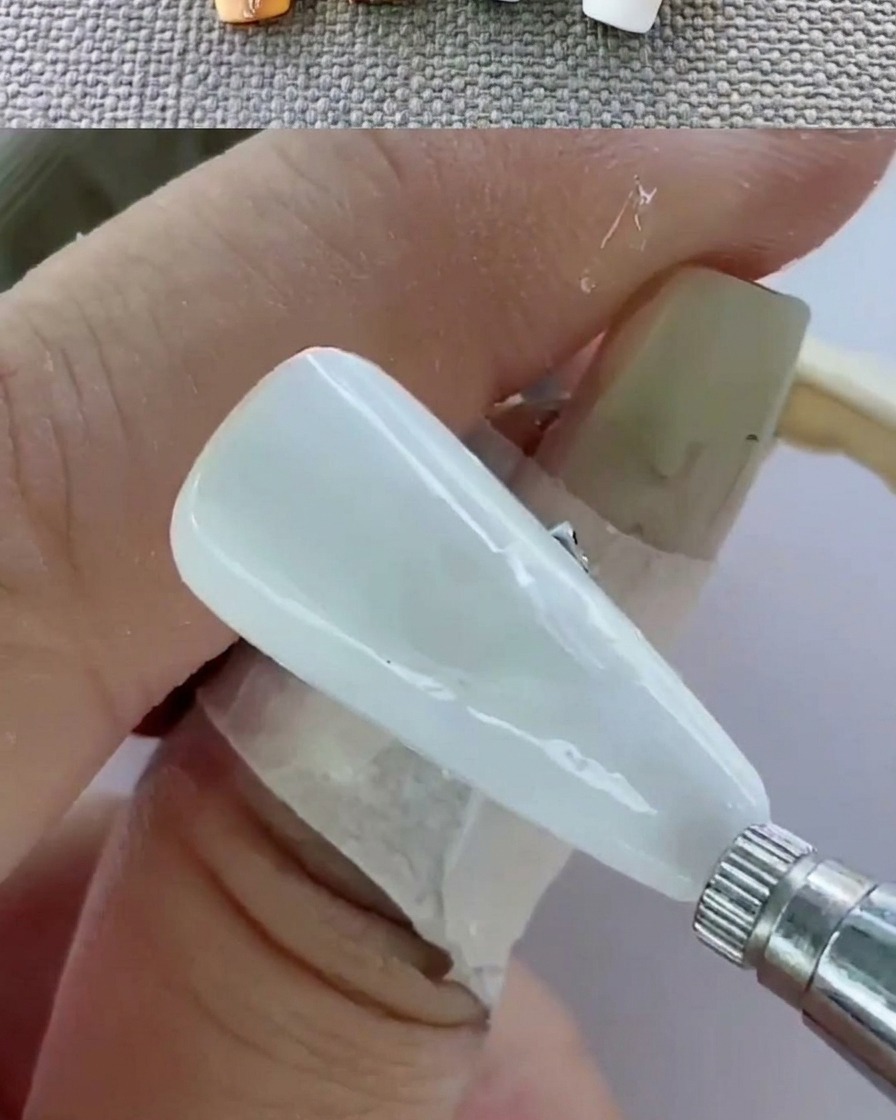 Vista en primer plano de una mano dentro de una lámpara UV curando las uñas.