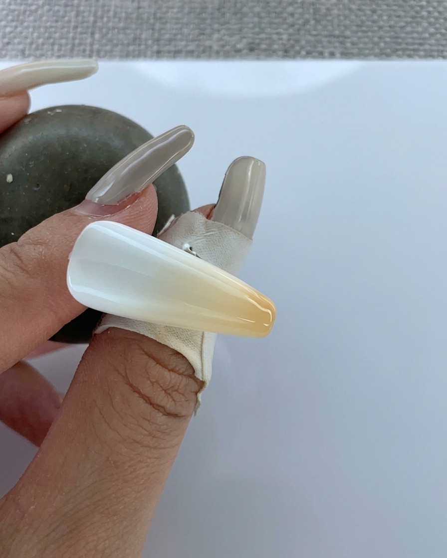 Un pincel aplicando top coat transparente sobre el degradado aerografiado terminado.