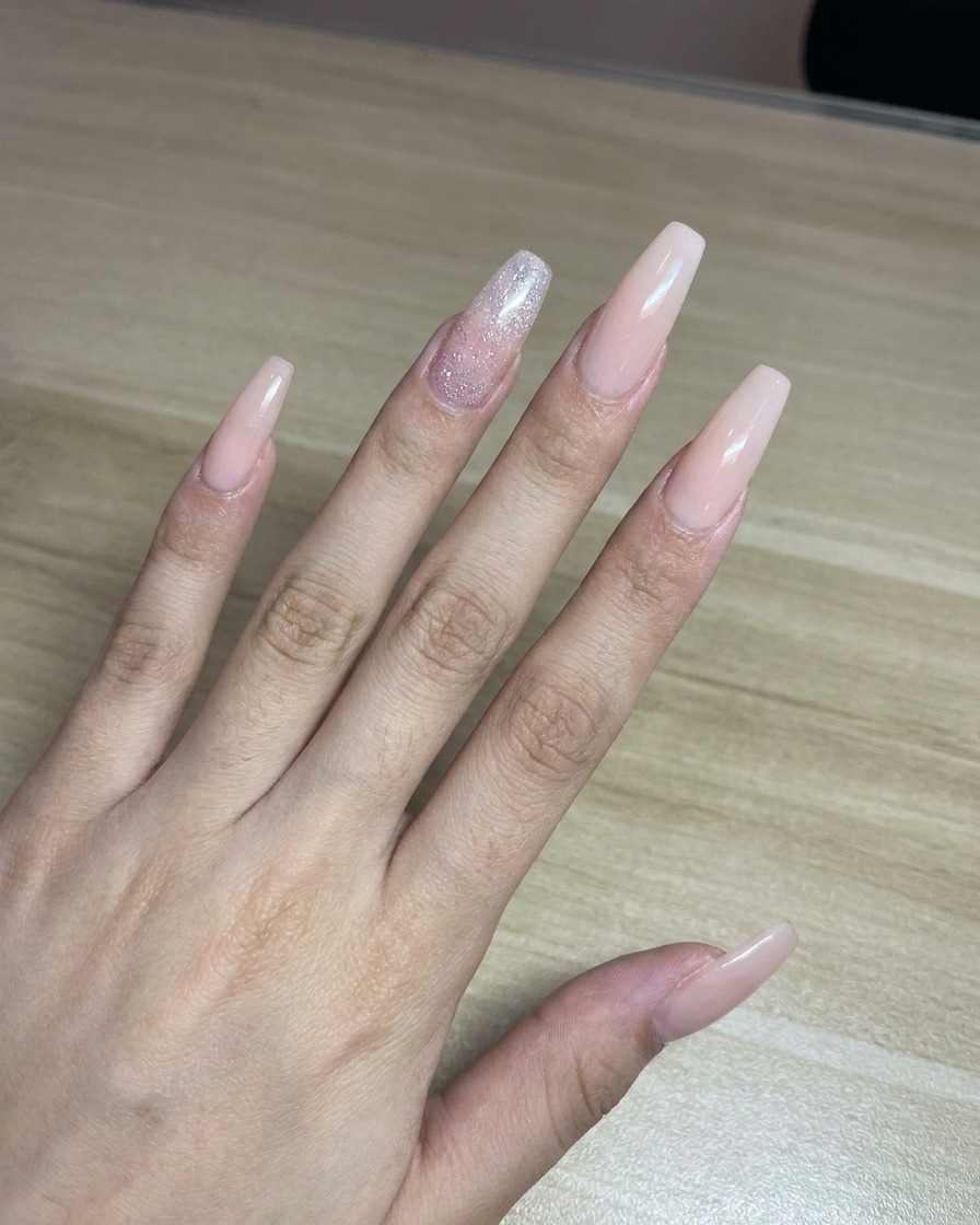 Una técnica rociando pintura rosa desde un aerógrafo sobre un trozo de papel blanco como prueba antes de aplicarlo en las uñas.