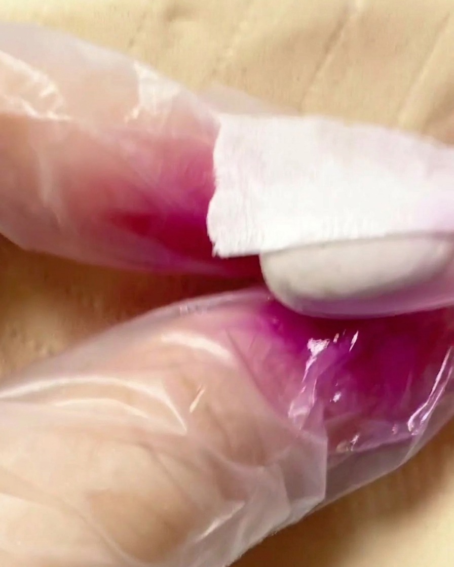 Un aerógrafo aplicando una bruma de pigmento morado sobre la segunda mitad del tip.