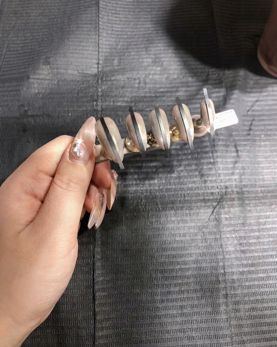 Un aerógrafo aplicando la primera capa de gel blanco en spray al segundo set de uñas.
