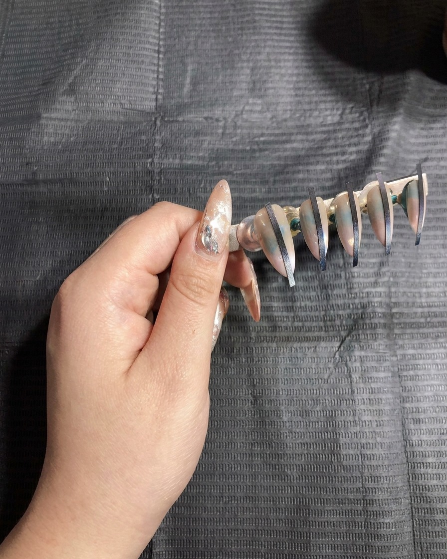 Un soporte de uñas con uñas artificiales colocadas dentro de una lámpara UV para curar.