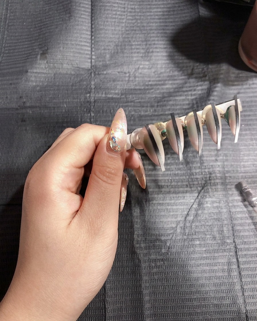 Uñas artificiales sobre un soporte curándose bajo la luz brillante de una lámpara UV.