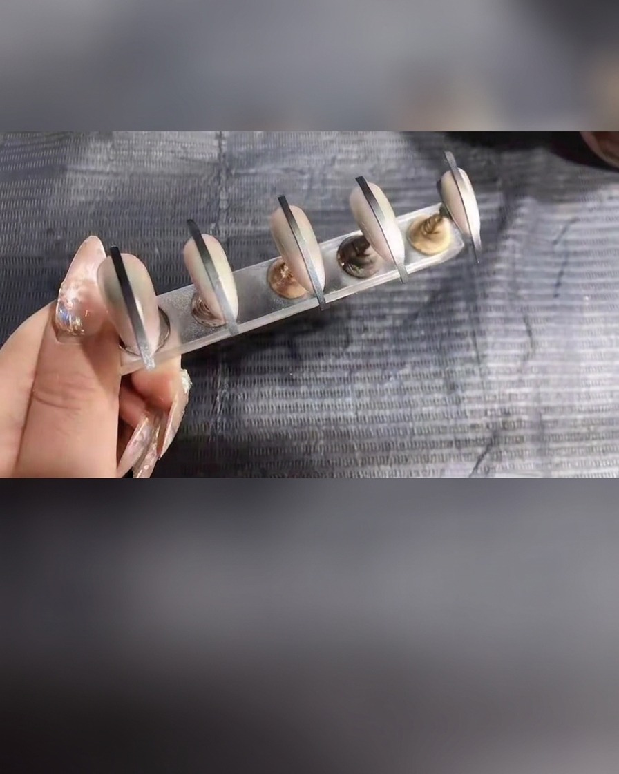 Primer plano de uñas en un soporte recibiendo una última aplicación ligera de gel en spray.