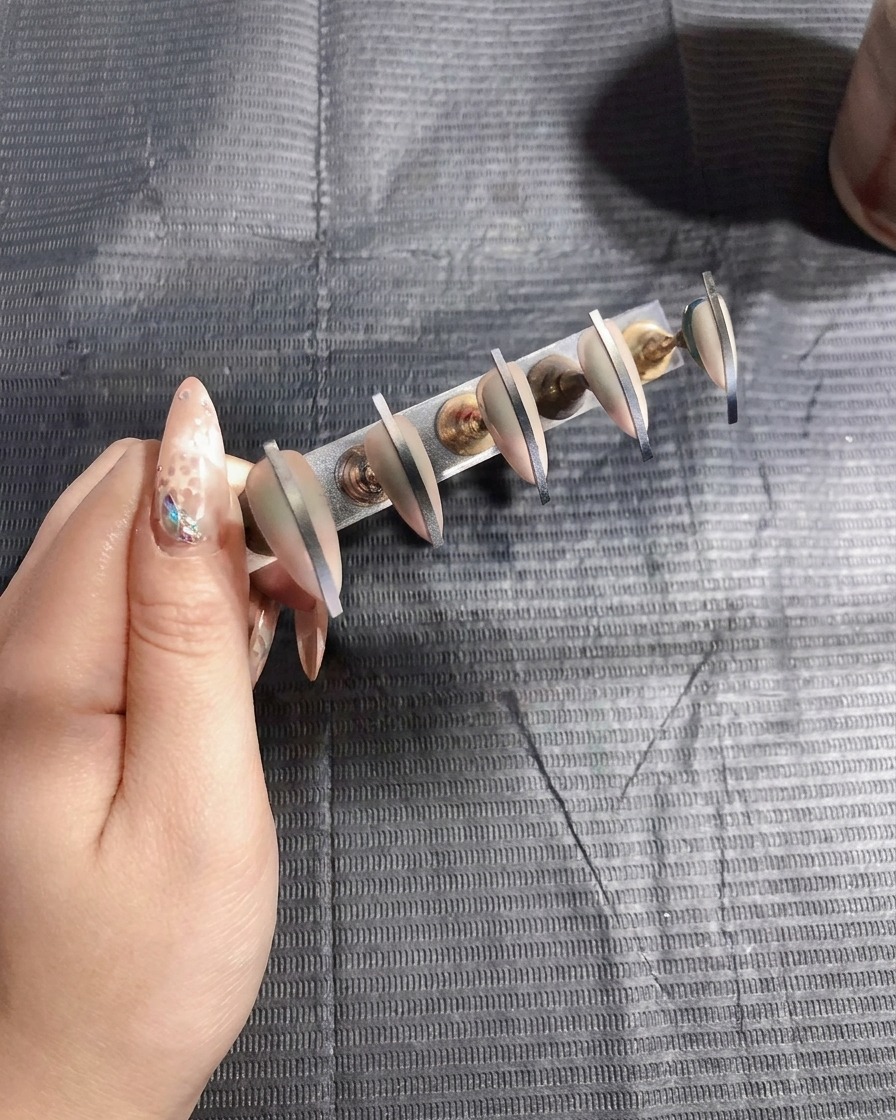 Uñas artificiales siendo curadas bajo una lámpara UV, señalando la finalización de la aplicación del color.