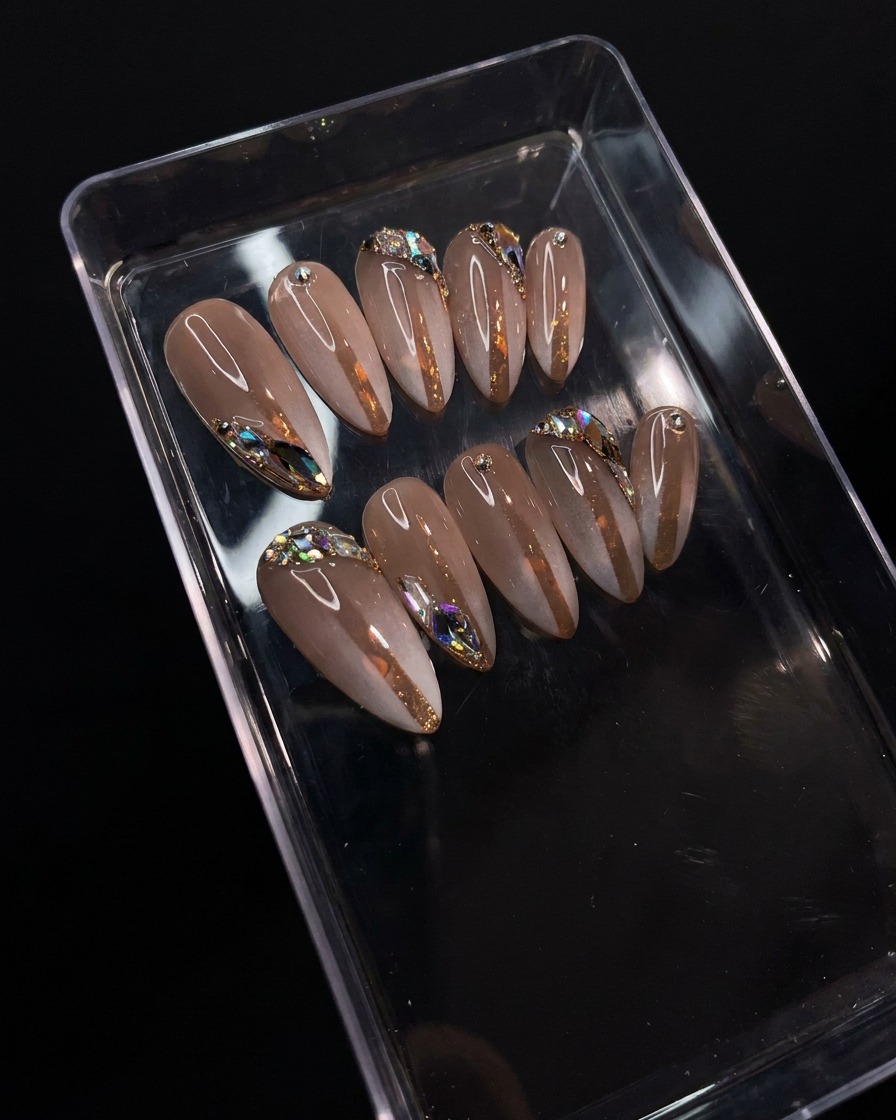 Un pincel aplicando un top coat transparente y brillante sobre el diseño detallado de degradado y pedrería.