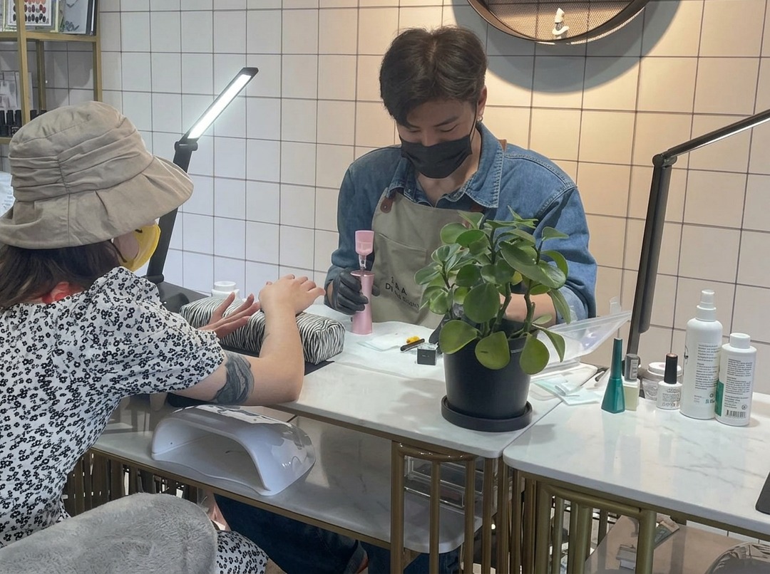 Primer plano de una manicurista usando un pincel pequeño para aplicar cuidadosamente la base de gel transparente en la uña.