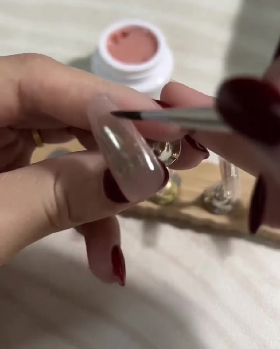 Cepillando una capa suave de esmalte nude claro sobre la base previamente curada.