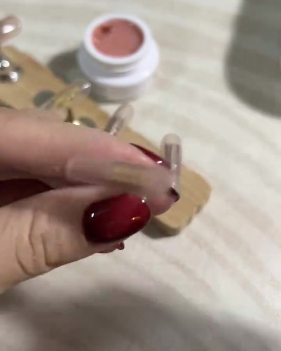 Primer plano de una mano usando una toallita sin pelusa con limpiador de gel sobre uñas press-on.