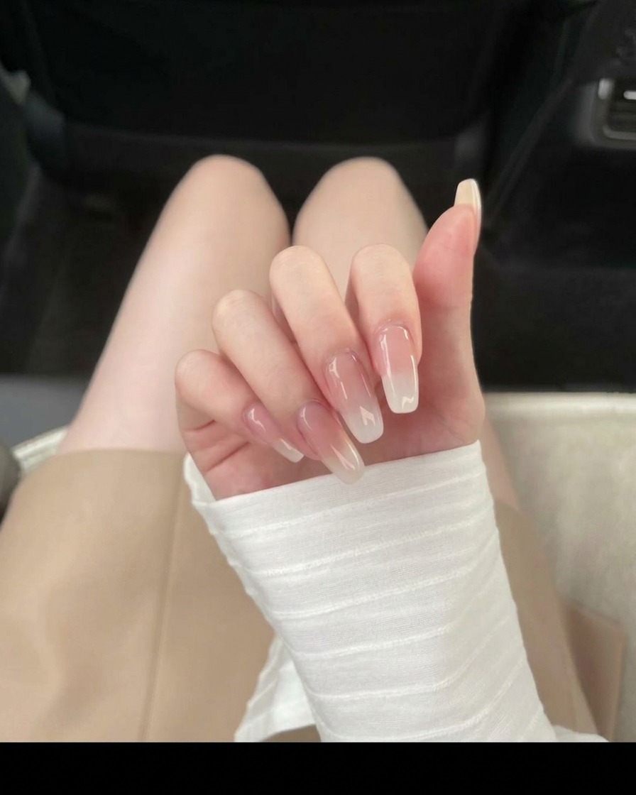 Aplicando esmalte de gel nude hielo translúcido en la superficie de la uña.