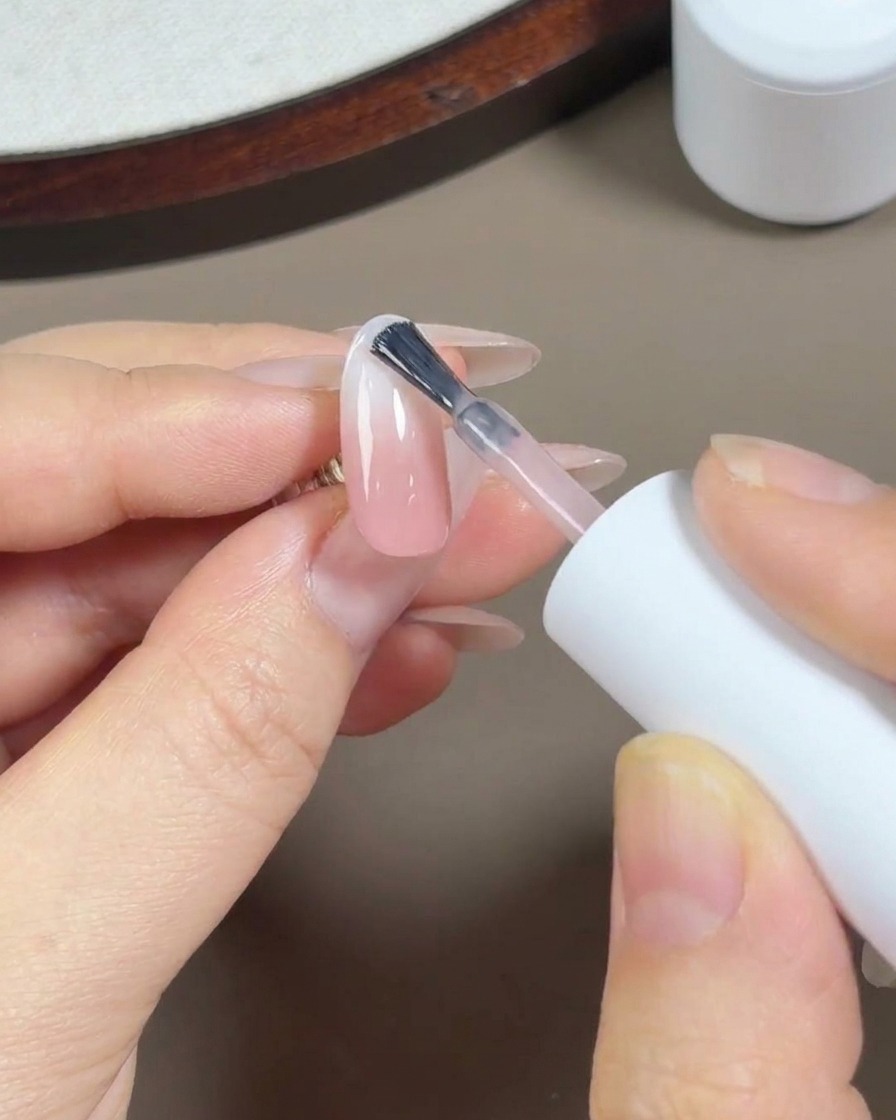 Sosteniendo una botella de top coat, lista para su aplicación.
