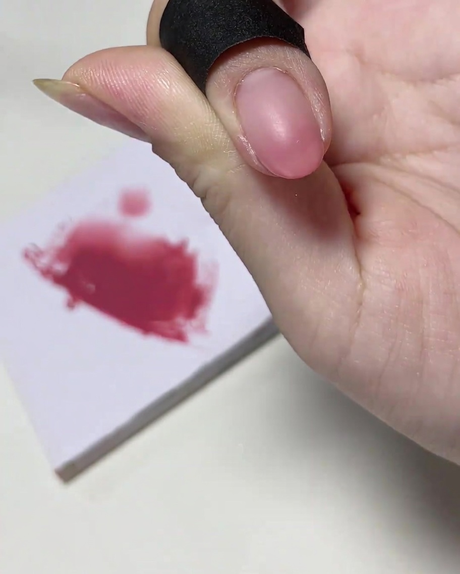 Un pincel para uñas añadiendo una cantidad concentrada de esmalte en gel rosa en la misma punta de la uña.
