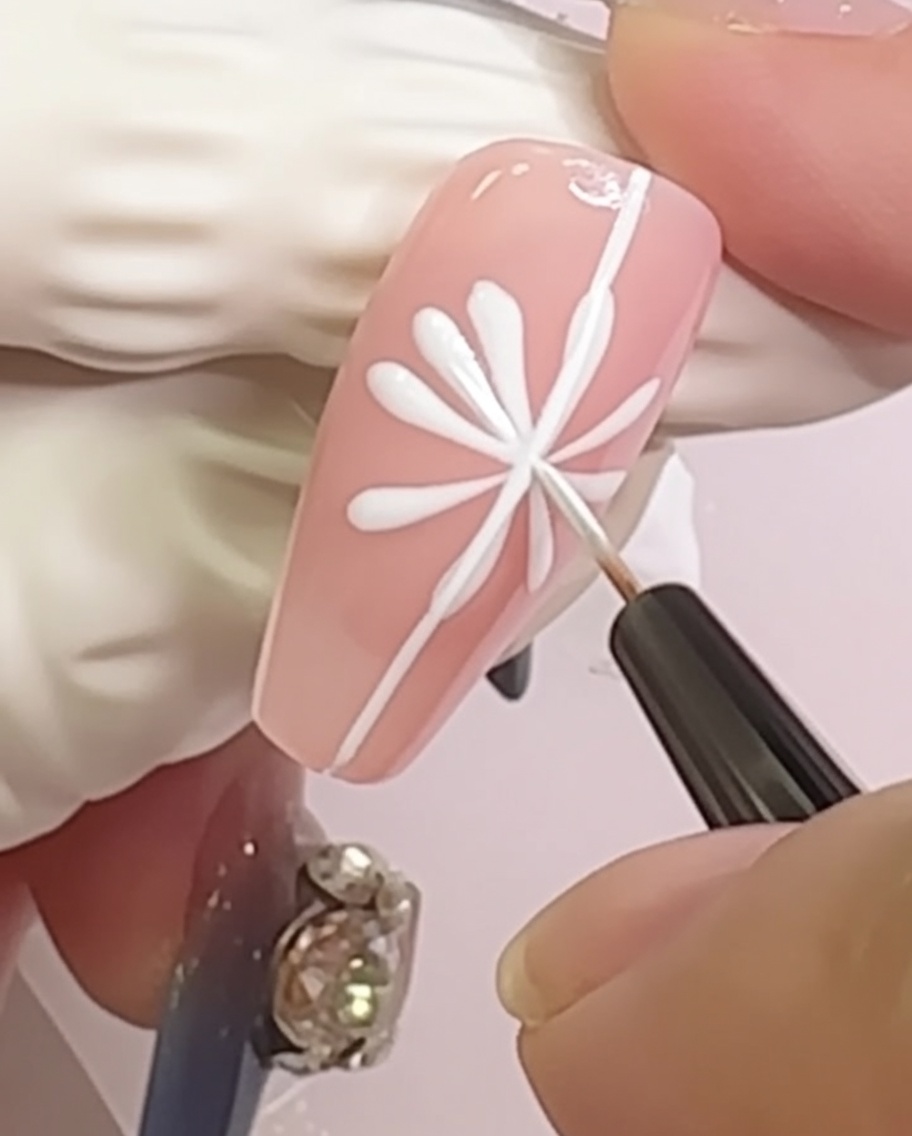 Una uña que muestra un diseño de margarita con pequeñas formas de pétalos redondeados añadidos en las puntas de las líneas radiales.
