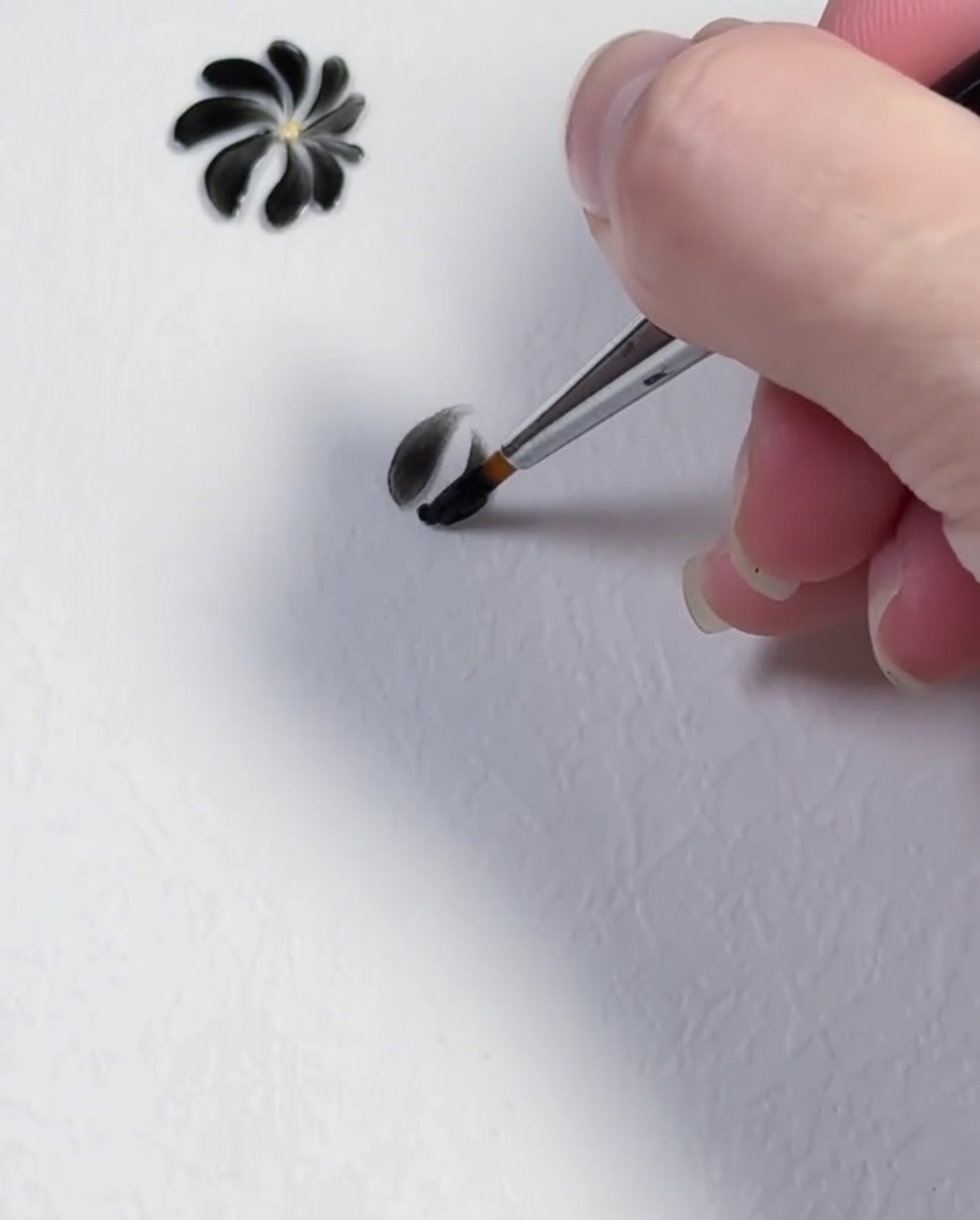 Un trazo de pincel formando el tercer pétalo negro de un diseño de margarita.