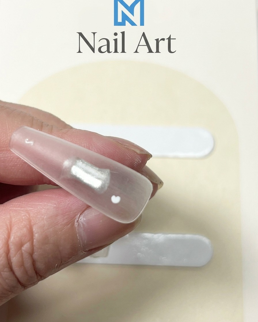 Primer plano de un tip de uña transparente con un punto de gel blanco espeso aplicado en el centro.