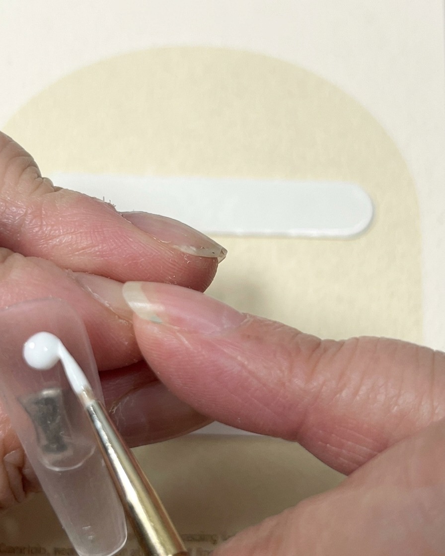 Un pincel liner arrastrando gel blanco desde un punto central para crear el aspecto de remolino de un capullo de rosa.