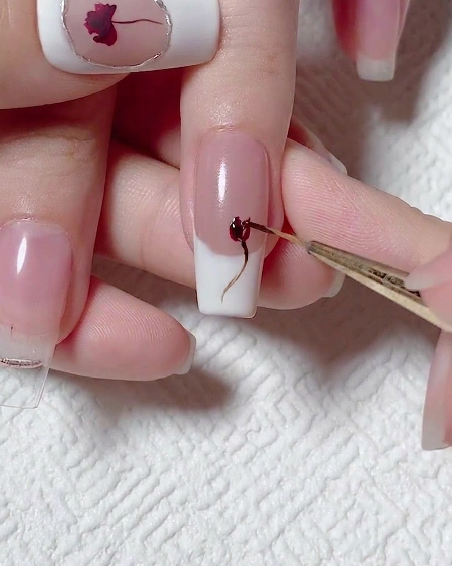 Primer plano de un pincel de detalle añadiendo profundidad al diseño de rosa con gel rojo.