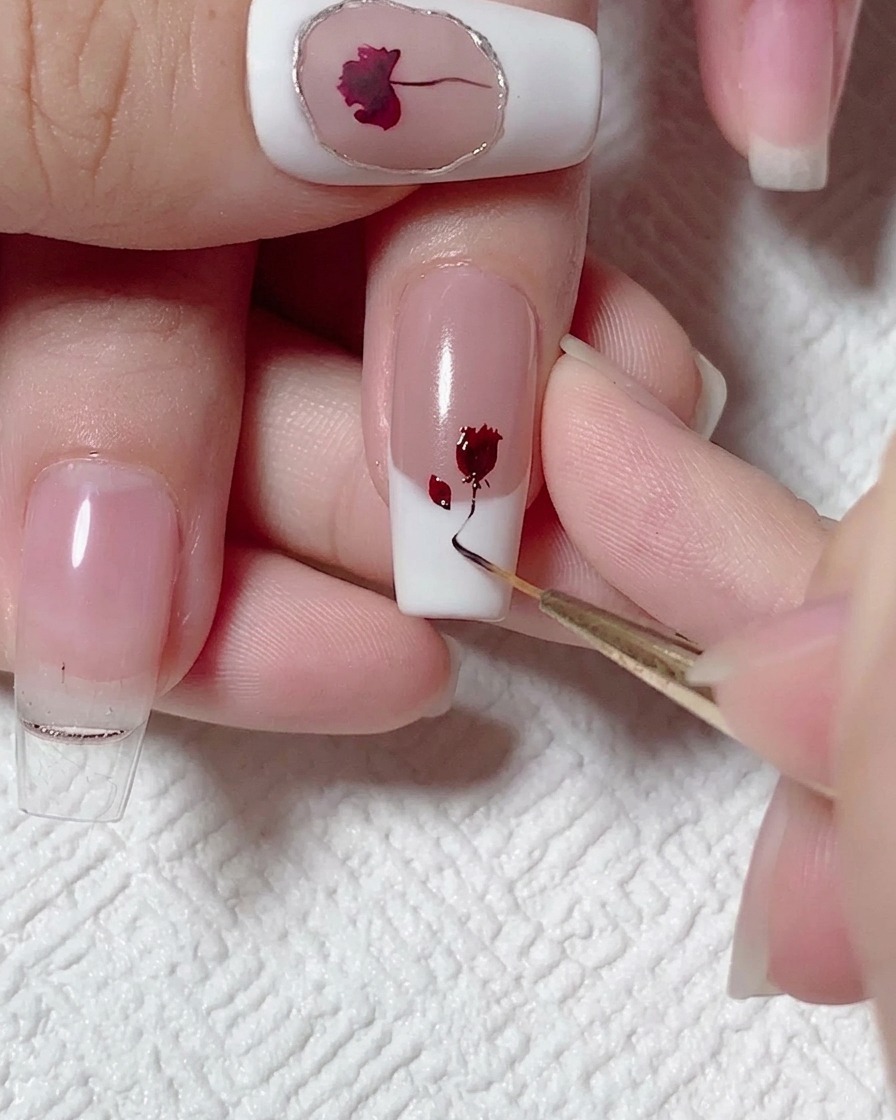 Un pincel liner trazando una línea fina de gel marrón oscuro hacia abajo desde la rosa.