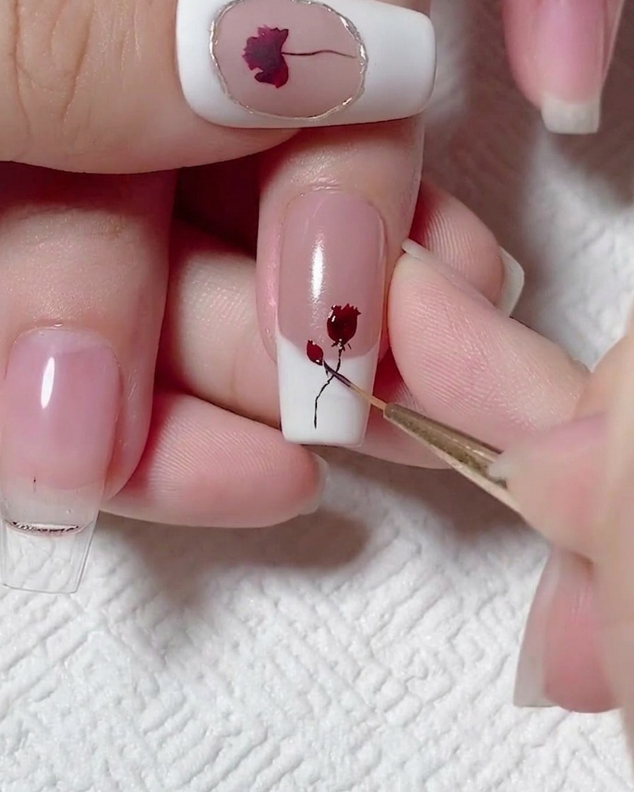 Un pincel liner añadiendo hojas pequeñas al tallo negro y rosa roja.