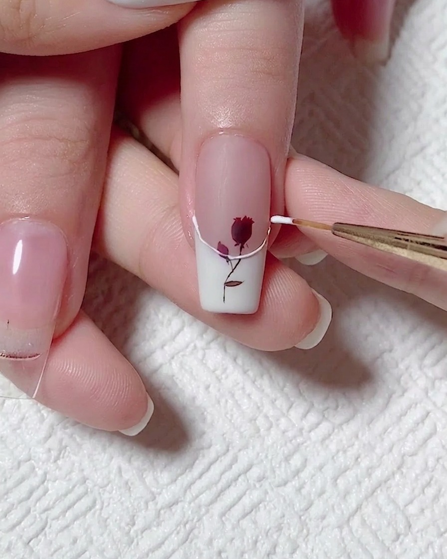 Un pincel liner trazando el borde de la francesa blanca con gel de relieve 3D transparente.