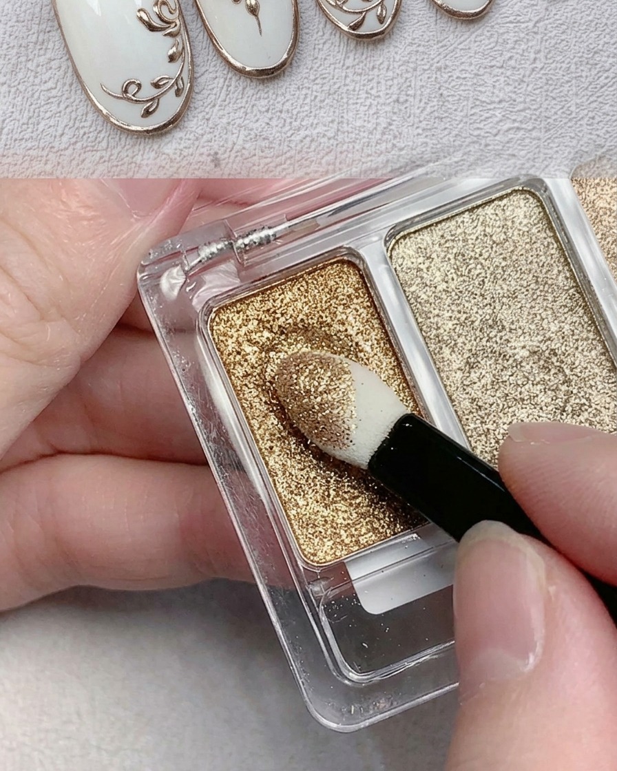 Un aplicador de esponja para sombras de ojos tomando polvo cromo metálico dorado de una paleta.