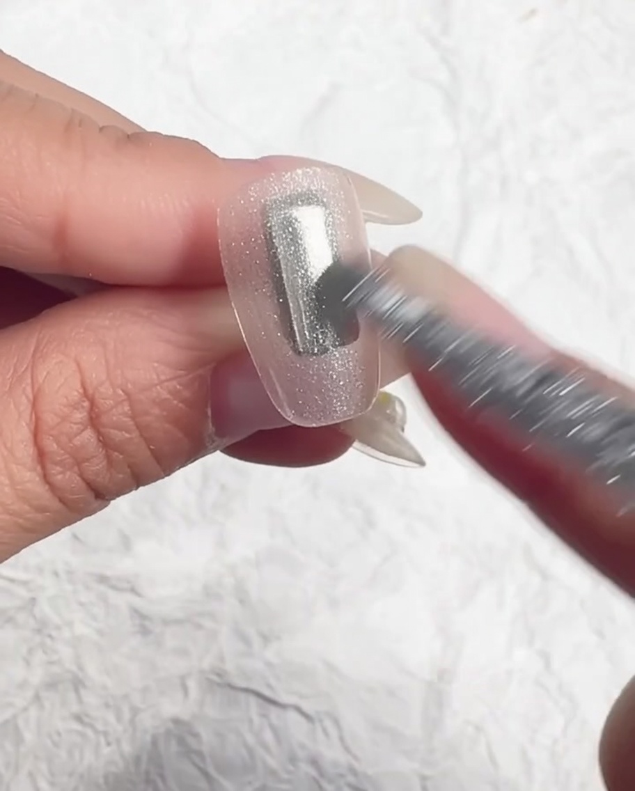 Un pincel nivelando el gel translúcido sobre la uña.
