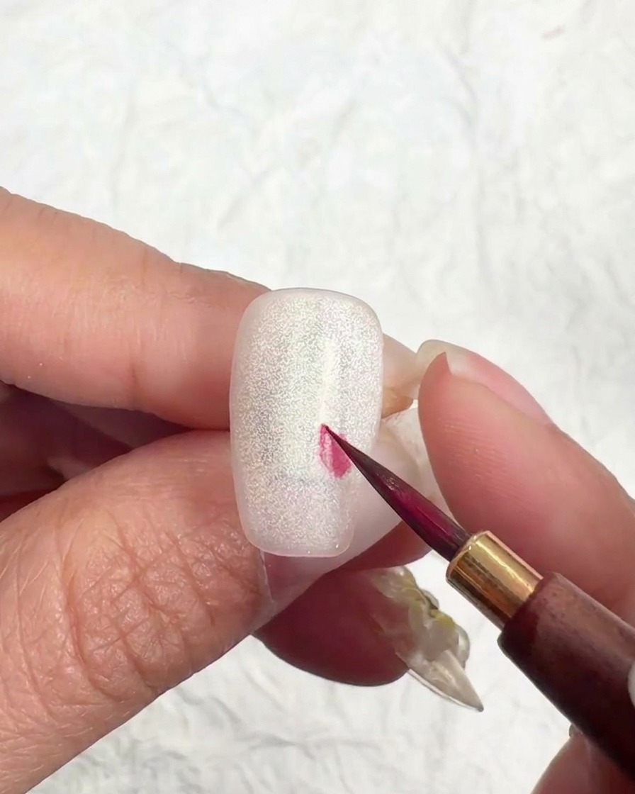 Pincel liner arrastrando el color hacia afuera desde un punto central para dar forma al pétalo.