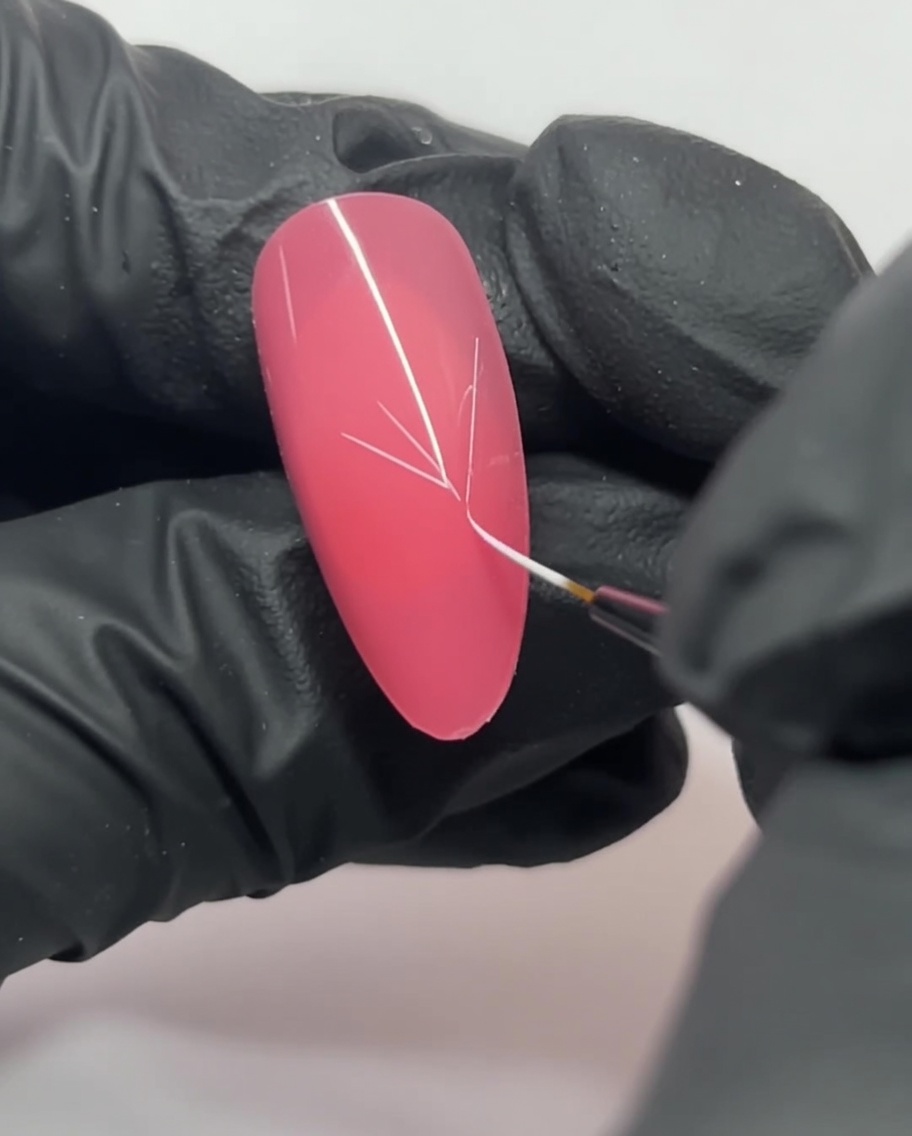 Primer plano de una uña rosa que muestra líneas blancas que se cruzan para formar una guía en forma de Y.